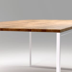 May include: A rectangular wooden table with a light brown surface and a white metal frame. The table's top is made of wood and the legs are a bright white color. The table is a modern design.
