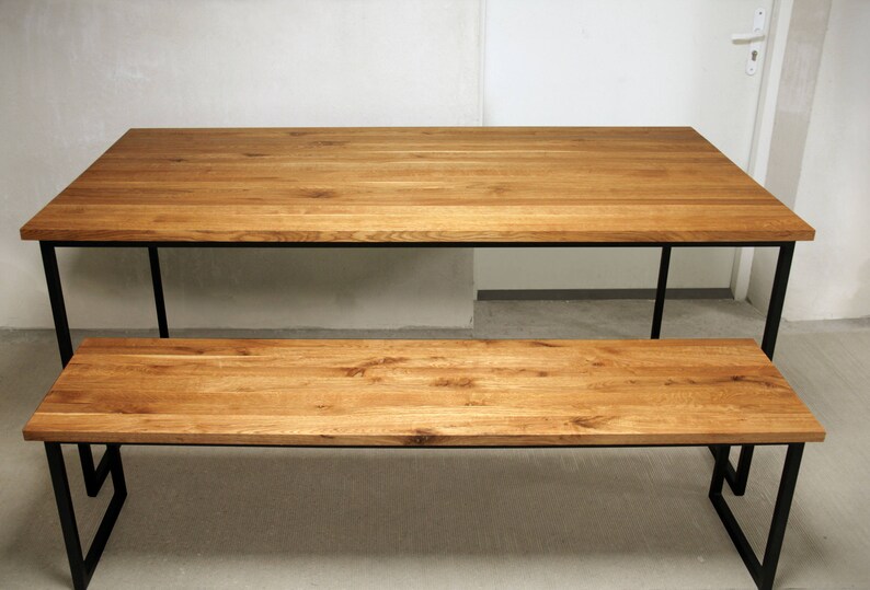 May include: A wooden dining table and bench set. The table and bench have a natural wood finish and black metal legs. The table is rectangular, and the bench is a smaller version of the table. The set is suitable for a dining room or kitchen.