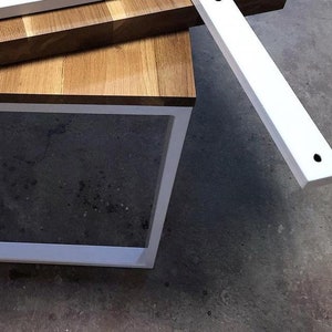 May include: A white metal frame with a wood top. The frame is made of two pieces of metal that are joined together at the corners. The wood top is made of several pieces of wood that are joined together to create a checkered pattern.