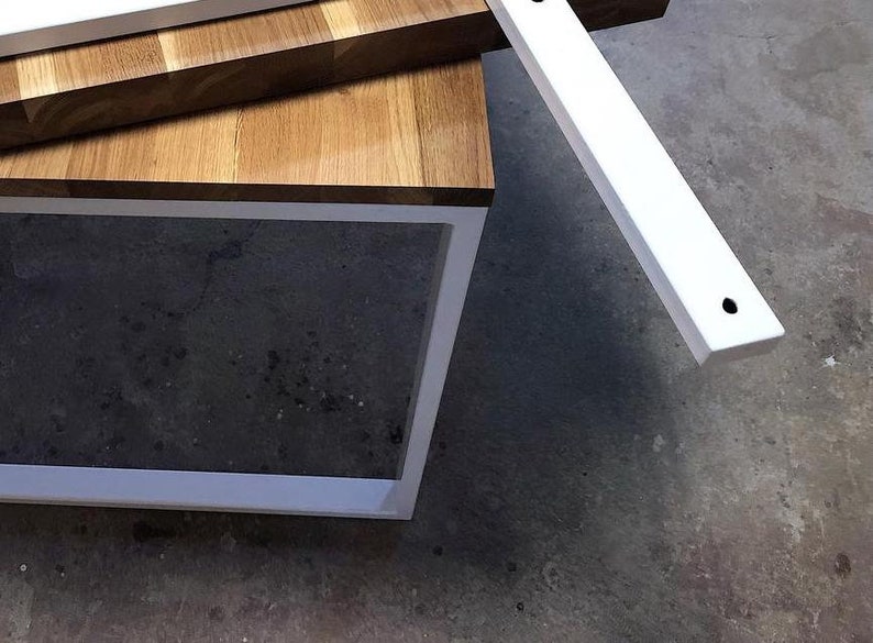 May include: A white metal frame with a wood top. The frame is made of two pieces of metal that are joined together at the corners. The wood top is made of several pieces of wood that are joined together to create a checkered pattern.