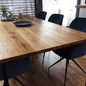 May include: A wooden dining table with a natural finish and black metal legs. The table is surrounded by six dark blue velvet chairs.