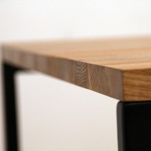 May include: A wooden table top with a natural wood grain finish. The table top is supported by black metal legs.