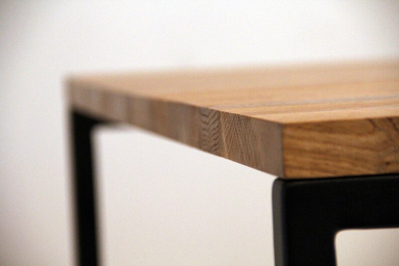 May include: A wooden table top with a natural wood grain finish. The table top is supported by black metal legs.