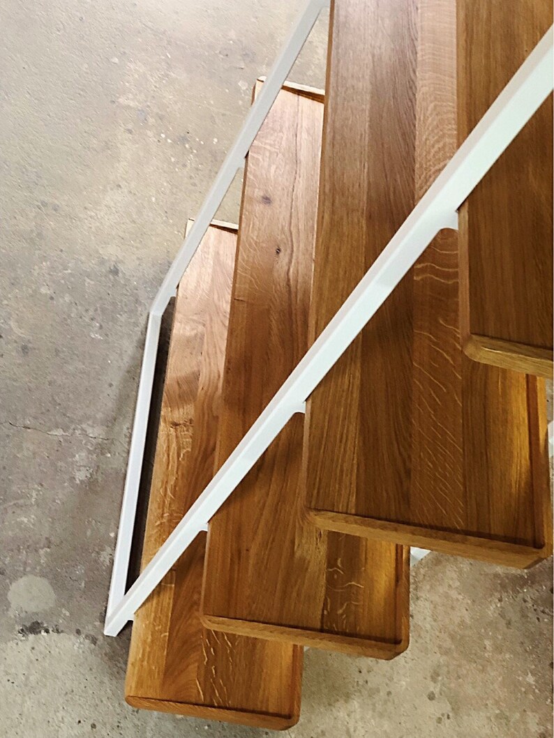 Puede incluir: Una estanter&iacute;a de metal blanco con cuatro estantes de madera. Los estantes son de madera natural con un acabado marr&oacute;n claro. Los estantes est&aacute;n inclinados y la unidad se ve desde arriba.
