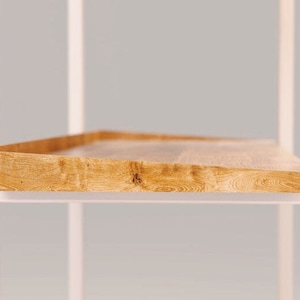 Puede incluir: Una estanter&iacute;a de metal blanco con un estante de madera. El estante est&aacute; hecho de madera natural de color marr&oacute;n claro y tiene una textura ligeramente rugosa.