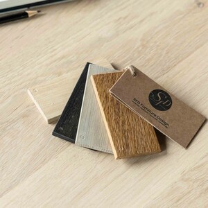K&ouml;nnte beinhalten: Vier Holzproben in verschiedenen Braunt&ouml;nen, Schwarz und Wei&szlig;, mit einem braunen Etikett mit der Aufschrift "SFD Furniture Design".
