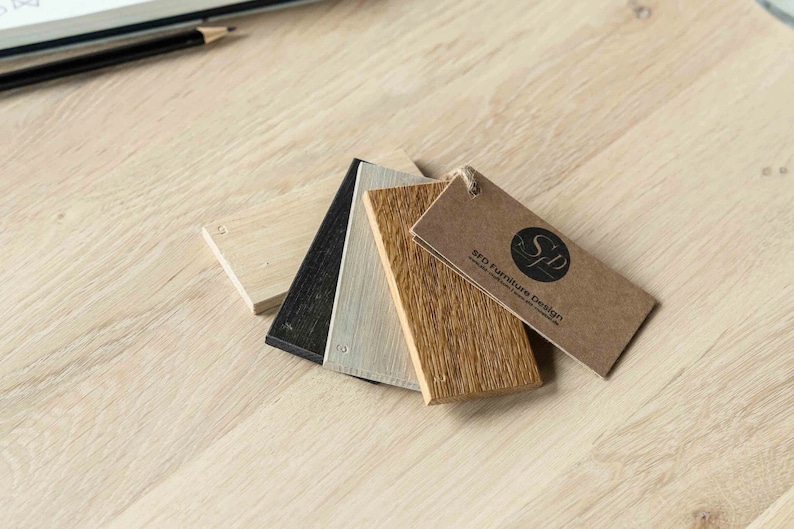 K&ouml;nnte beinhalten: Vier Holzproben in verschiedenen Braunt&ouml;nen, Schwarz und Wei&szlig;, mit einem braunen Etikett mit der Aufschrift "SFD Furniture Design".