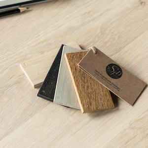 May include: Four wood samples in different shades of brown, gray, and white, with a brown tag that reads "SFD Furniture Design".