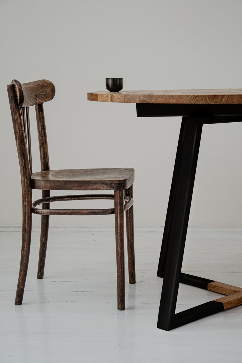 May include: A dark brown wooden chair with a curved back and a round table with a black metal base. The table top is made of light brown wood.