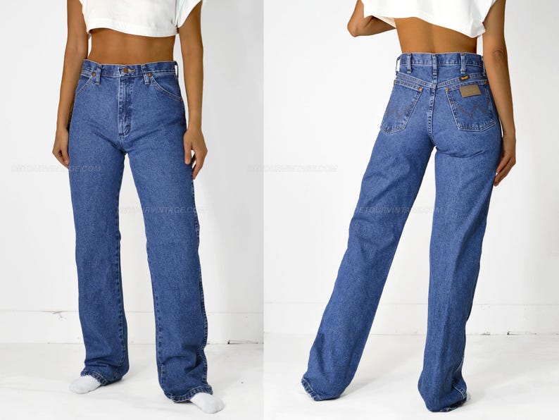 May include: A pair of blue denim jeans with a high waist and a straight leg fit. The jeans have a classic five-pocket design and a leather patch on the back waistband.