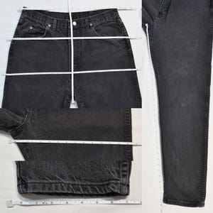 May include: Black denim jeans with a classic five-pocket design. A white measuring tape shows the waist, inside leg, and leg opening measurements. The jeans are laid flat on a white surface for measurement.
