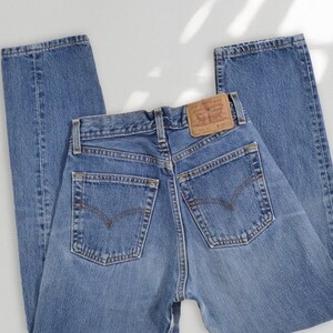 Puede incluir: Unos vaqueros de mezclilla azul con dise&ntilde;o de cintura alta, dos bolsillos traseros, una etiqueta de cuero beige en la cintura con el logotipo de Levi Strauss & Co., trabillas para cintur&oacute;n y una peque&ntilde;a etiqueta roja en la costura del bolsillo.