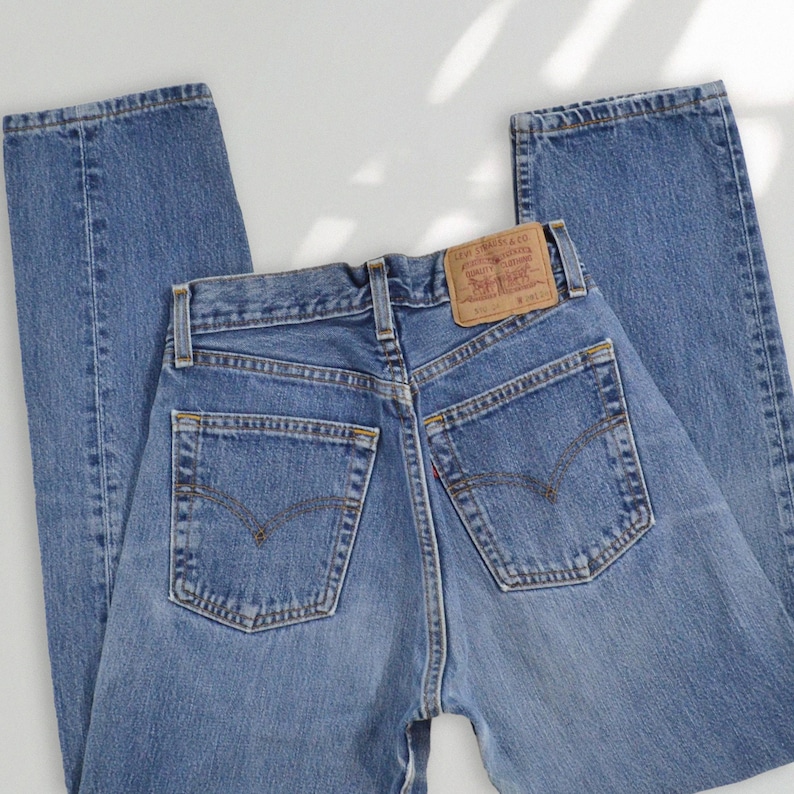 Puede incluir: Unos vaqueros de mezclilla azul con dise&ntilde;o de cintura alta, dos bolsillos traseros, una etiqueta de cuero beige en la cintura con el logotipo de Levi Strauss & Co., trabillas para cintur&oacute;n y una peque&ntilde;a etiqueta roja en la costura del bolsillo.