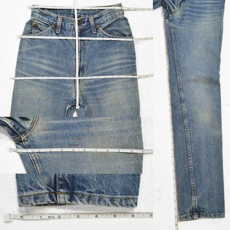 May include: Light blue denim jeans with a faded wash. The jeans are laid flat with a measuring tape across the waist, inseam, and leg opening. The jeans have a classic five-pocket design and a button and zipper closure.