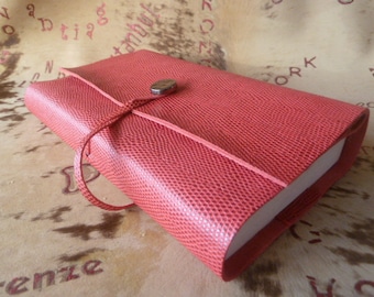 427-adjustable book cover in red grained goatskin, for books up to 18 cm high, with tie closure and decorative piece.