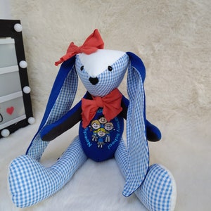 May include: Blue and white gingham bunny rabbit plush toy with a red bow and embroidered logo that says "Newdigate Nursery School".