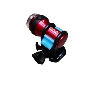 Puede incluir: Un soporte GoPro rojo y negro con una luz Exposi Trade azul y blanca unida a él.