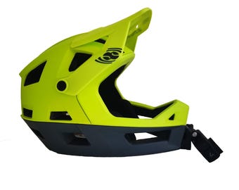Puede incluir: Un casco de bicicleta integral de color amarillo brillante con una visera negra y un logotipo negro en el lateral. El casco tiene una correa de barbilla negra y un soporte negro para una cámara o luz en el lateral.
