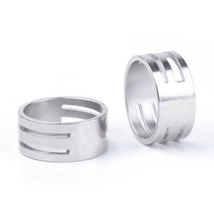 May include: Two silver metal rings with three horizontal slits cut into the side of each ring.