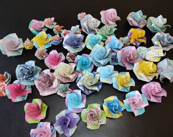 May include: A collection of origami flowers made from fabric in various colors and patterns, including blue, pink, yellow, green, and purple.