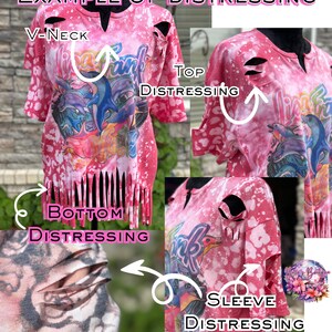 May include: A pink distressed V-neck top with a colorful graphic design. The shirt features distressed details on the sleeves, top, and bottom. The text "EXAMPLE OF DISTRESSING" is at the top of the image.