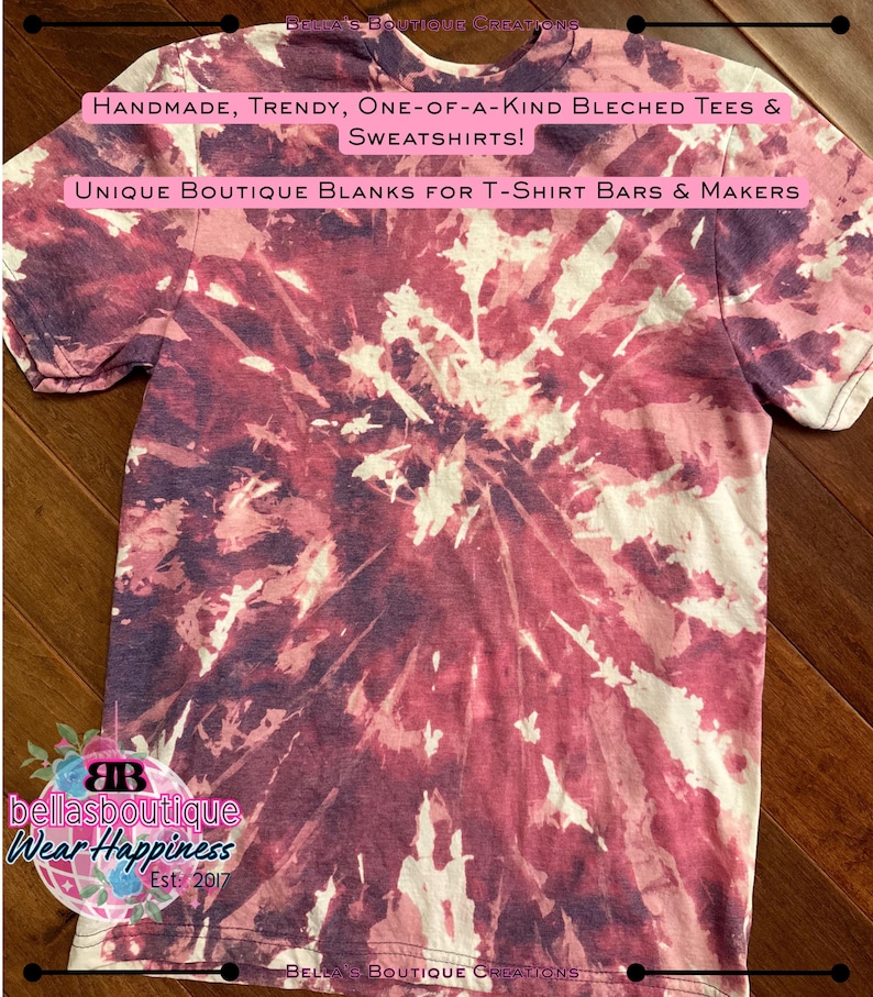 May include: A short-sleeved t-shirt with a tie-dye pattern in shades of burgundy, white, and purple. The shirt features text that reads "HANDMADE, TRENDY, ONE-OF-A-KIND BLECHED TEES & SWEATSHIRTS!" and "UNIQUE BOUTIQUE BLANKS FOR T-SHIRT BARS & MAKERS".