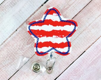 Könnte beinhalten: Ein roter und weiß gestreifter sternförmiger Badgehalter mit blauem Rand und einer transparenten, einziehbaren Badge-Spule.