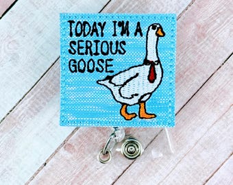 Puede incluir: Portagafete de tela azul con un ganso blanco que lleva una corbata roja y el texto "Today I'm a Serious Goose".