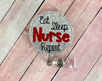 Könnte beinhalten: Silberner Glitzer-Badgehalter mit einer roten und schwarzen Stickerei mit der Aufschrift "Eat Sleep Nurse Repeat".