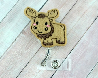 Può includere: Un porta badge retrattile in plastica trasparente con un alce ricamato marrone e beige con guance rosa.