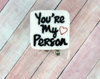 May include: White felt badge holder with a black embroidered message that reads "You're My Person" with a red heart.