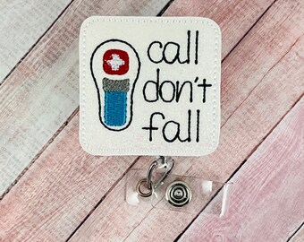 Könnte beinhalten: Weißer Badgehalter mit einem roten und blauen medizinischen Symbol und dem Text "call don't fall".