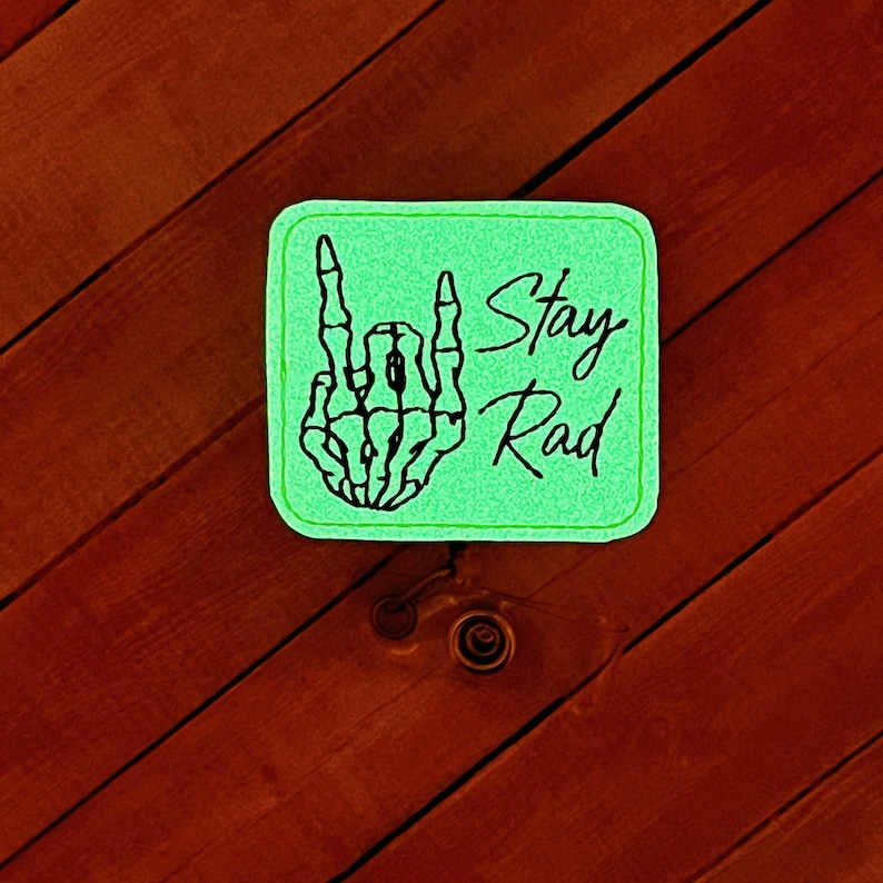 May include: Green square patch with a black skeleton hand giving the rock and roll sign. The text "Stay Rad" is written in black cursive.