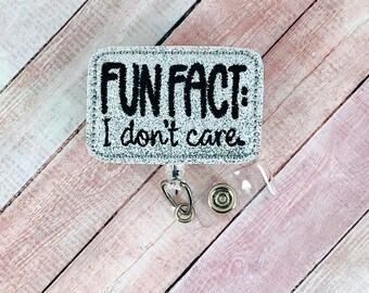 May include: Silver glitter badge holder with a black embroidered design that reads "Fun Fact: I don't care".