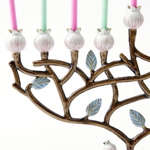 May include: A menorah with a tree branch design, featuring pink and blue floral accents. The menorah has eight candle holders and a shamash holder.