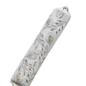 May include: White mezuzah with a silver design of pomegranates and a vine. The mezuzah has a silver Star of David at the top.
