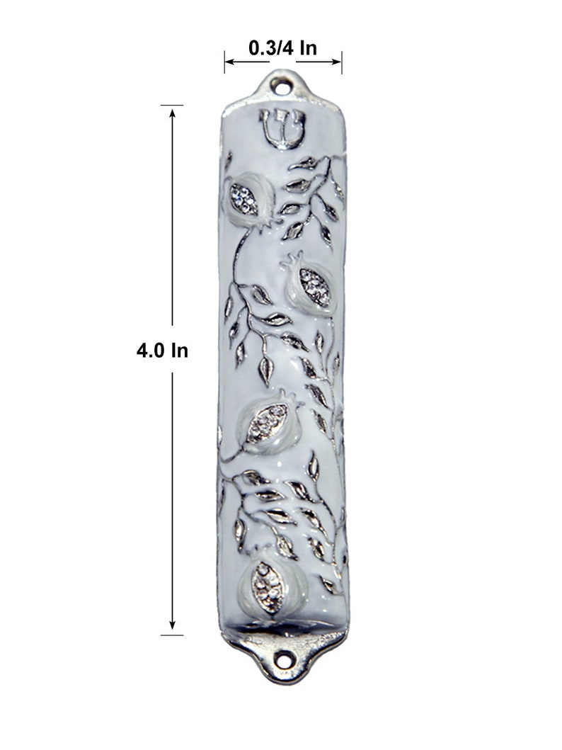May include: White mezuzah with a silver design of pomegranates and leaves. The mezuzah is 10 cm tall and 2 cm wide.