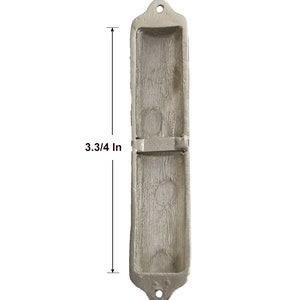 May include: A silver-coloured mezuzah case with a rectangular shape and a decorative design. The case is 3 3/4 inches tall and 0.3/4 inches wide.