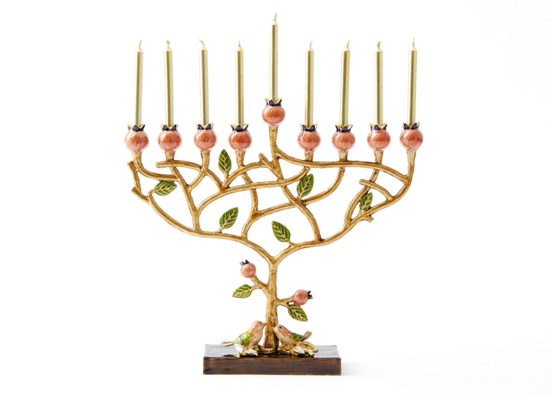 May include: A gold menorah shaped like a tree with pink pomegranate accents and green leaves. Two birds are perched on the base of the menorah.