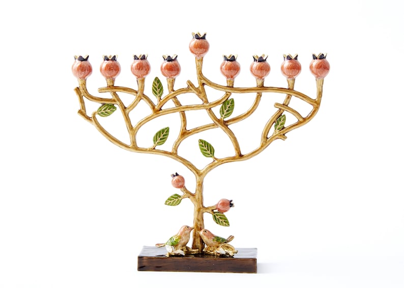May include: A gold menorah shaped like a tree with pink berries and green leaves. Two birds are perched on the base of the menorah, which is made of wood.