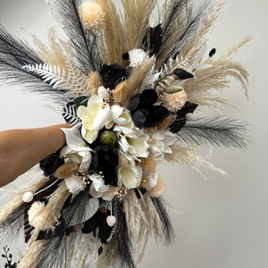 Puede incluir: Un ramo de flores secas con flores blancas y negras, hierba de la pampa y otras hojas secas.
