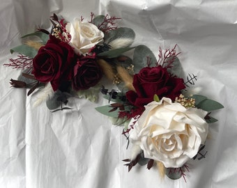 May include: Two burgundy and ivory silk rose flower arrangements with greenery and dried grasses. The arrangements are perfect for wedding decor or special events.