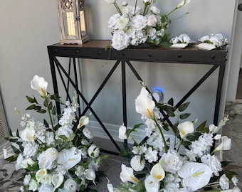 Arranjo de lírios-de-cala em arco no chão, decoração floral em branco e verde.