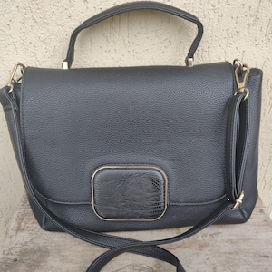 May include: Black leather satchel handbag with a gold trim and a snakeskin-textured flap. The bag has a top handle and a long adjustable shoulder strap.