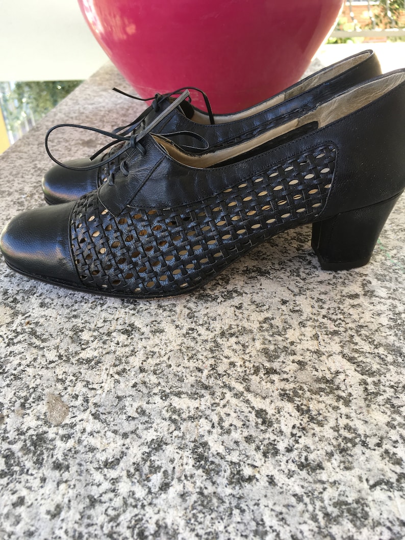 Puede incluir: Zapatos de cuero negro con un dise&ntilde;o tejido y un tac&oacute;n de bloque. Los zapatos tienen un cierre de encaje.