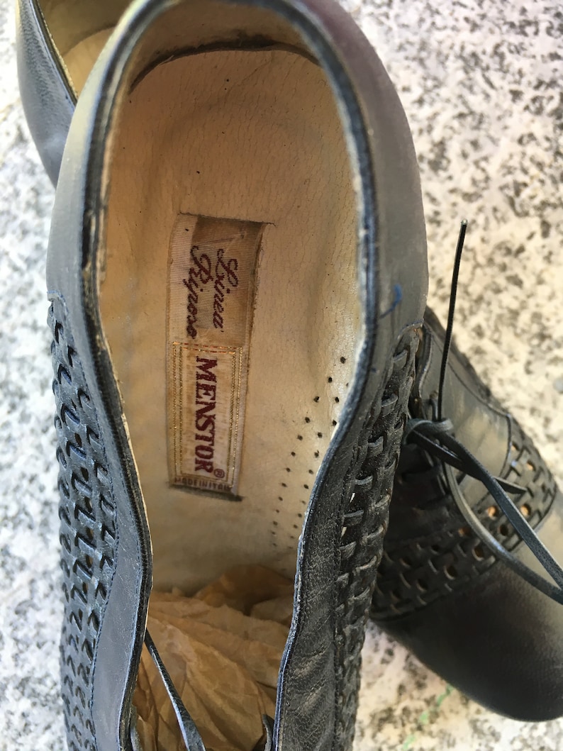 Puede incluir: Primer plano del interior de un zapato de cuero negro con un patr&oacute;n tejido. El zapato est&aacute; etiquetado con "Menstor" y "Linea Rigore".