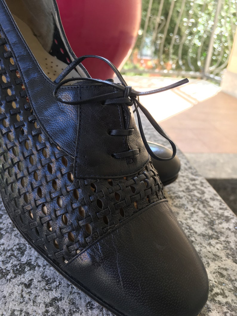 Puede incluir: Zapatos negros de cuero con cordones, con un patr&oacute;n tejido y punta cerrada.