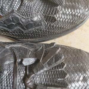 K&ouml;nnte beinhalten: Nahaufnahme eines Paares schwarzer Lederschuhe mit Quasten. Die Schuhe haben ein gewebtes Muster und eine strukturierte Oberfl&auml;che.