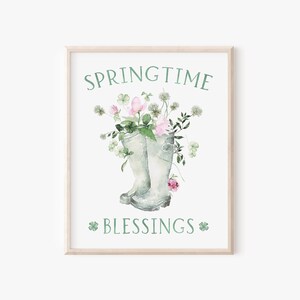 May include: A watercolor illustration of a pair of green rain boots filled with pink and white flowers. The text "SPRINGTIME BLESSINGS" is written in green below the boots.