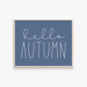 May include: A blue framed print with white text that says "hello autumn".